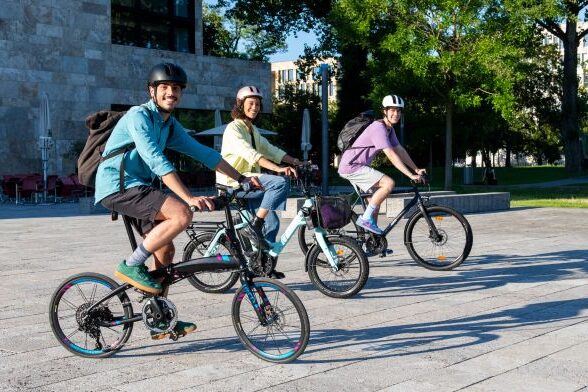 Drei Fahrradfahrer vor Gebäude