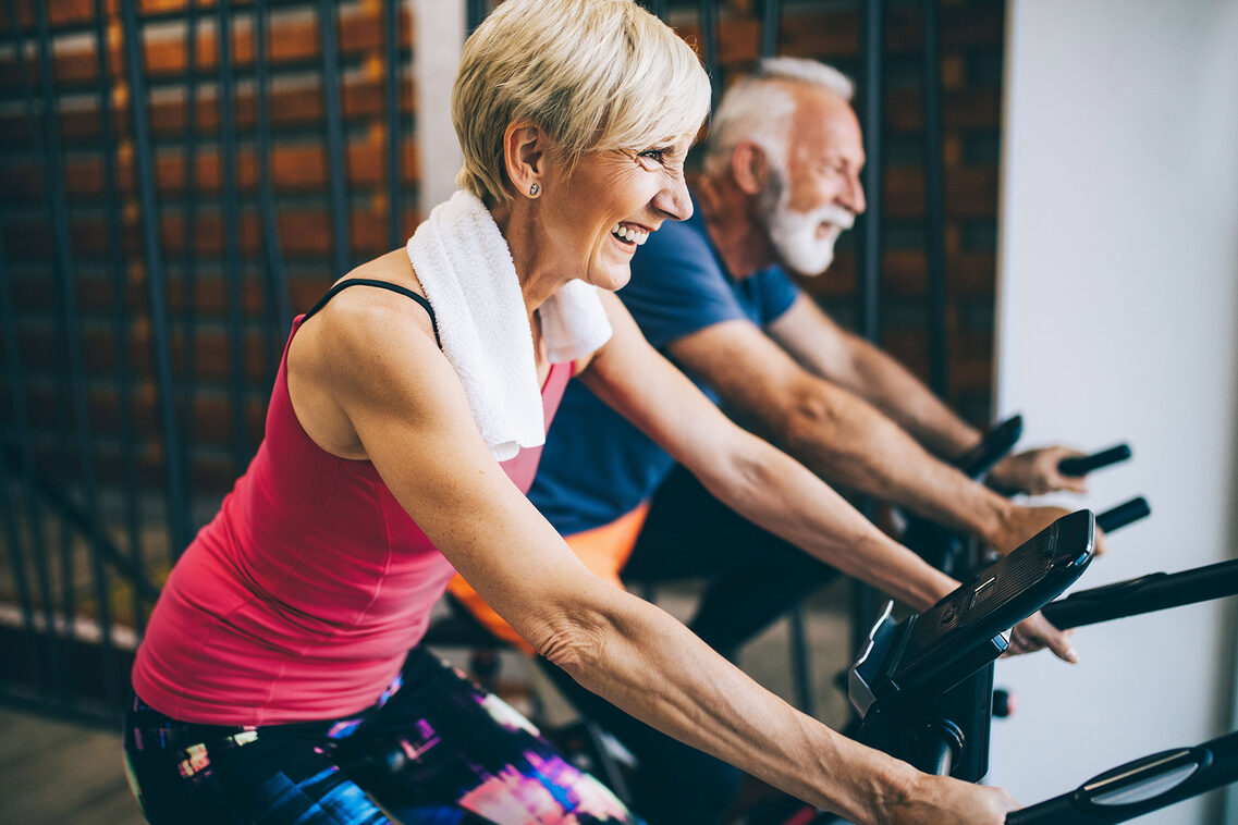 Seniorensportlerin und Seniorensportler auf den Indoorbike.