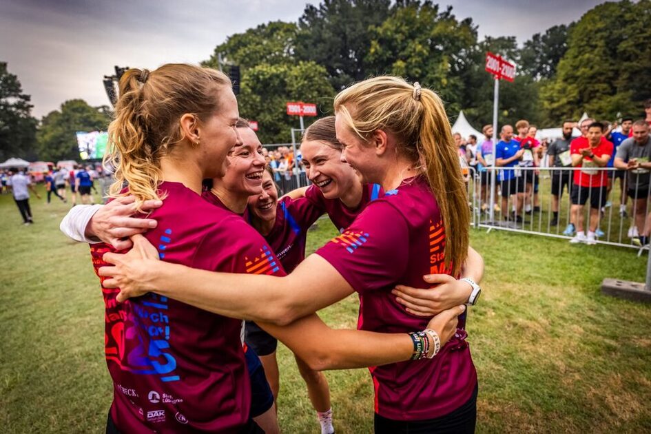 Junge Leute umarmen sich in Firmen-Trikots