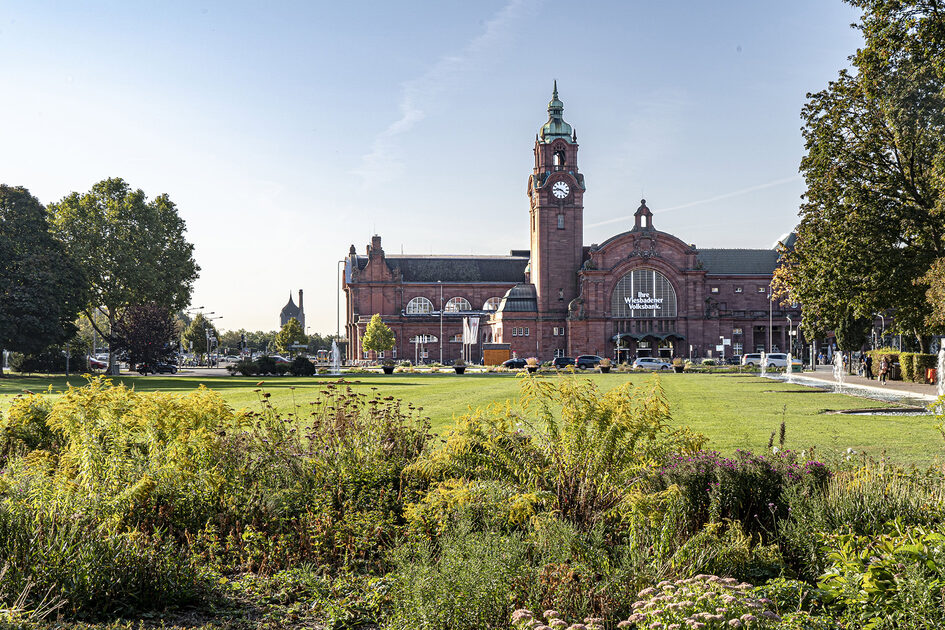 Historischer Hauptbahnhof vor Grünanlage.