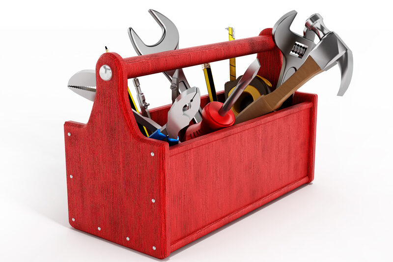 Roter Werkzeugkoffer aus dem unterschiedliche Werkzeuge und Bleistifte herausragen