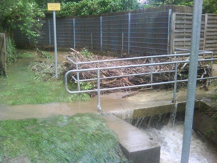 Durch Grünschnitt verstopfter Brückendurchlass führt zu Überschwemmung