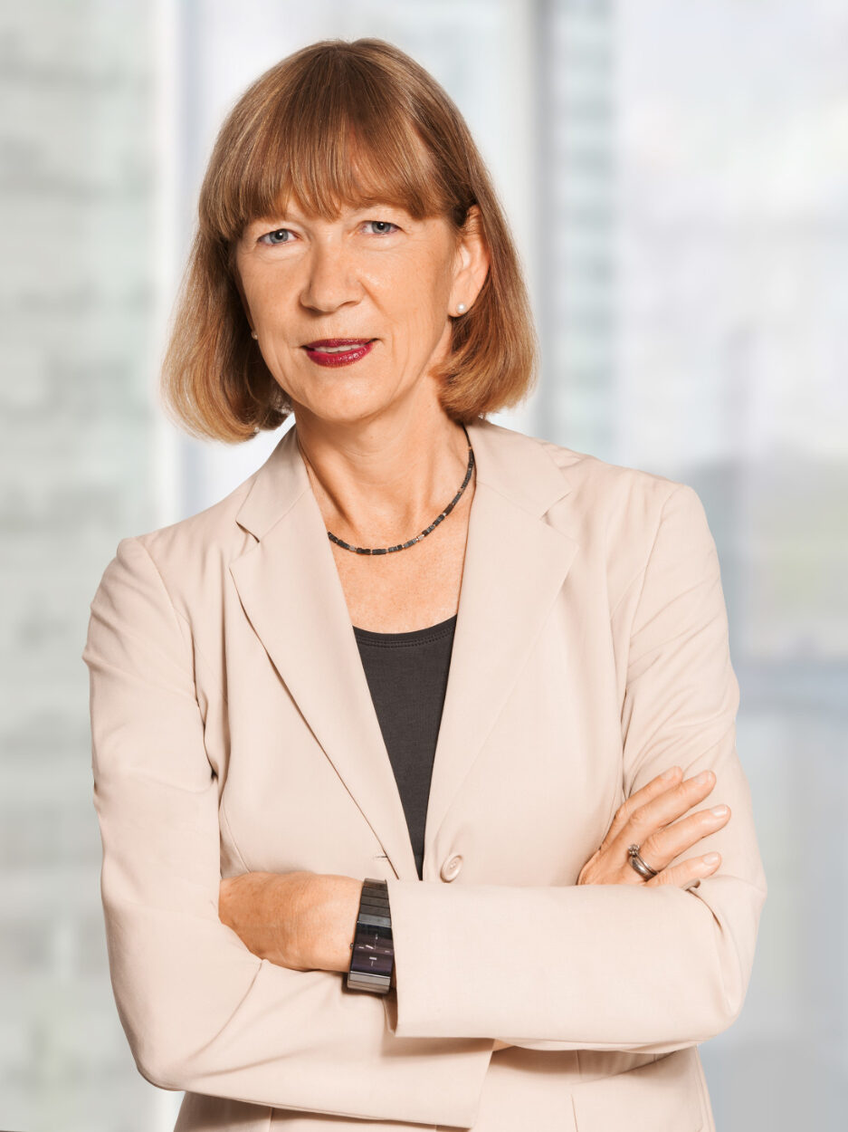 Eine Frau lächelt den Betrachter freundlich und interessiert an. Ihre Haltung drückt Energie und Konzentration aus.