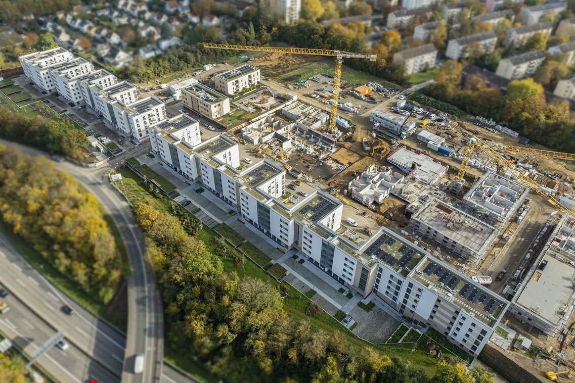 Drohnenaufnahme zeigt aus westlicher Blickrichtung, dass die Bebauung entlang der Saarstraße bereits fertiggestellt ist und die sich anschließenden Mehrfamilienhäuser sich im Bau befinden.