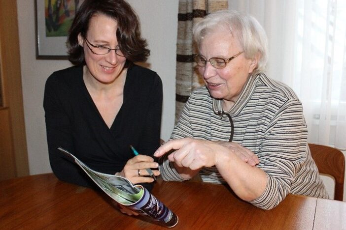 Beratungssituation – eine jüngere und eine ältere Frau sitzen an einem Tisch und schauen einen Katalog an.