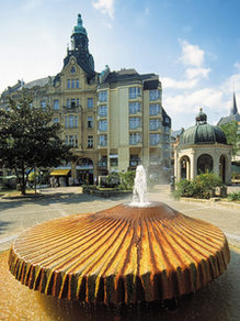 Kranzplatz meydanında fıskiye ve arka planda Kochbrunnen şadırvanı.