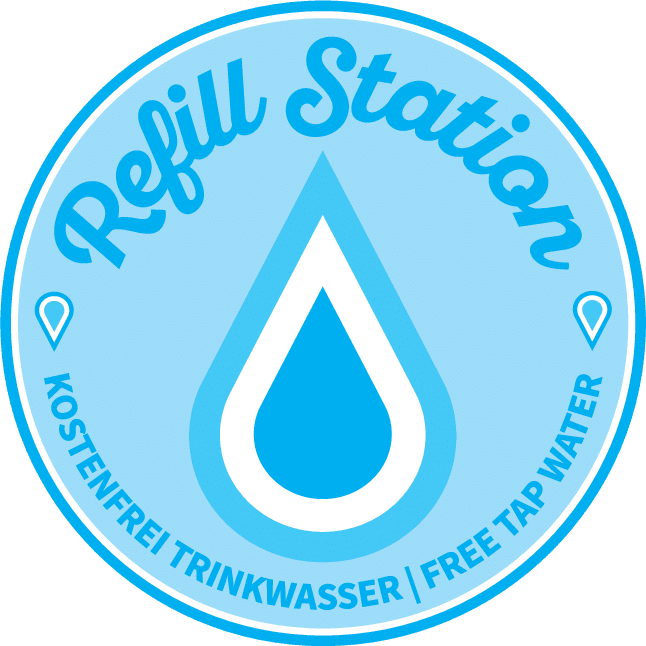 Runder blauer Aufkleber oben Schrift: Refill Station, darunter ist ein stilisierter Wassertropfen und unten der Text Kostenfrei Trinkwasser