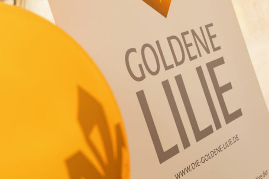 Ein gelber Ballon und ein weißer Schrift zu sind zu sehen. Dort steht "Goldene Lilie".