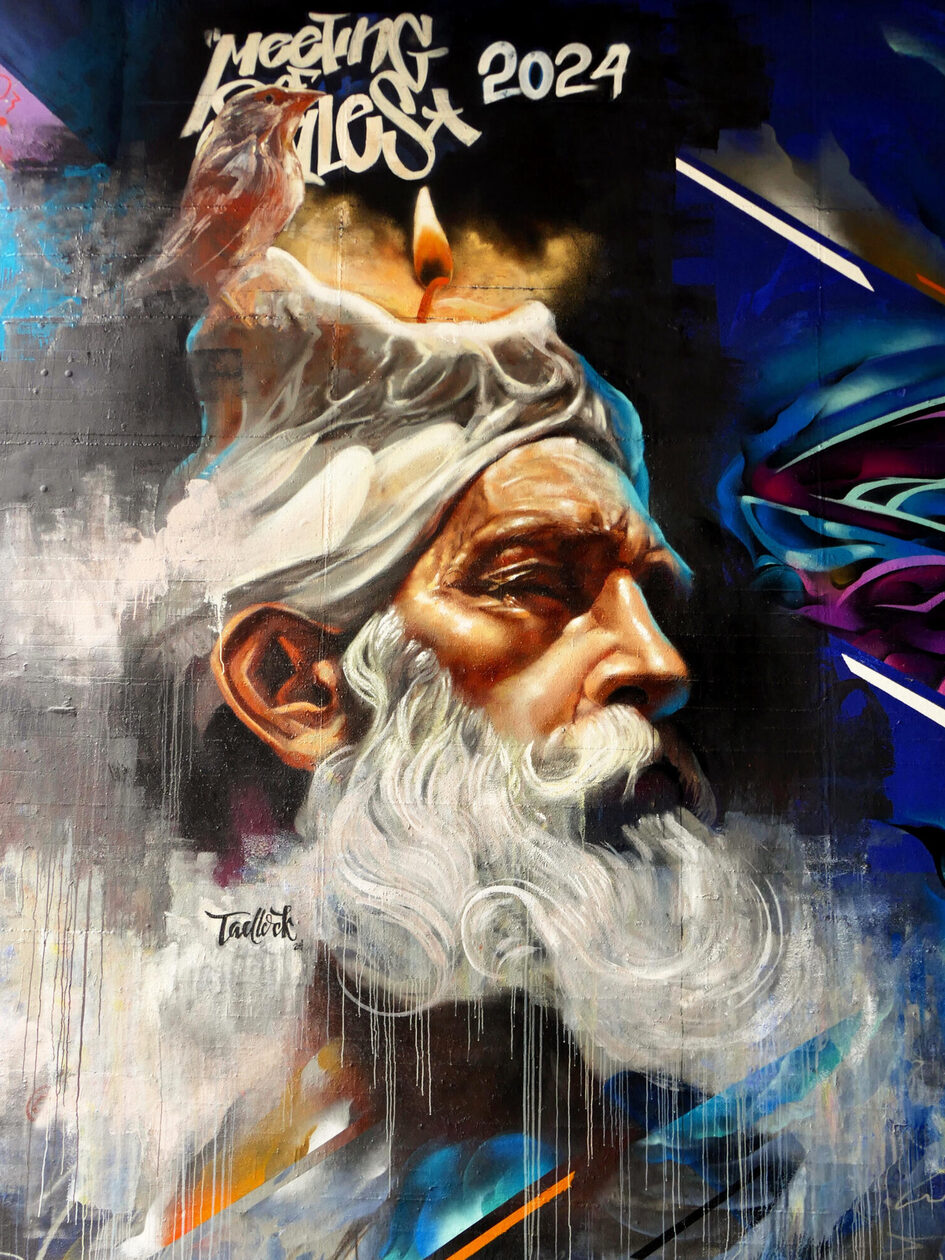 s Gesicht eine älteren Mannes mit weißem Bart. Auf seinem Kopf brennt eine Kerzen. Darüber steht "Meeting of Styles 2024".