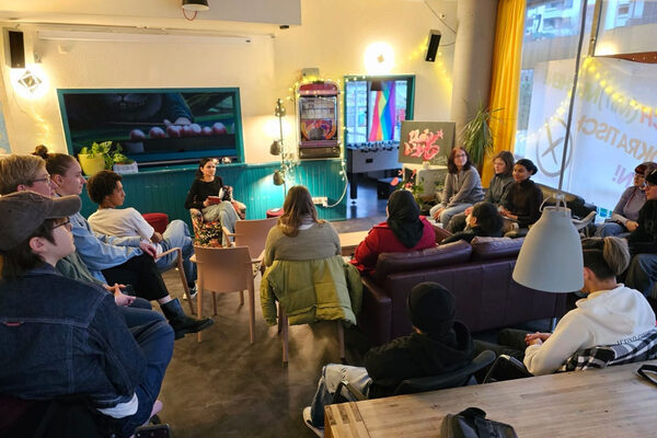 Several people sit together on sofas and chairs.