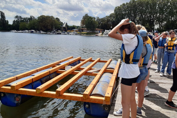 Mädchen mit Schwimmwesten stehen an einem Anleger am Wasser.