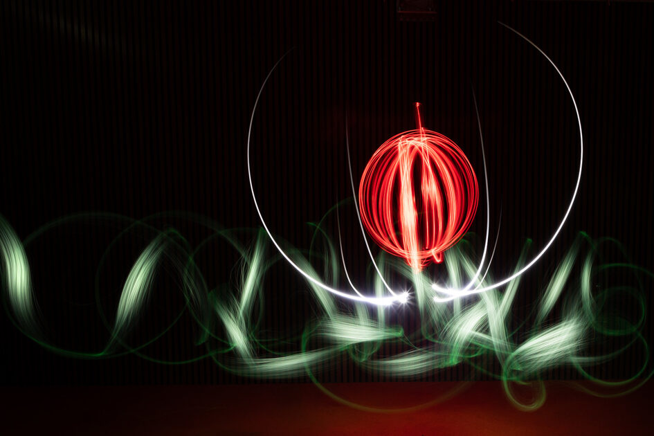 Rote und grüne Lichstrahlen bilden einen Kreis vor dunklem Hintergrund.