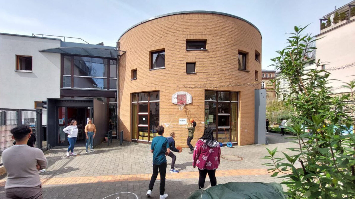 Jugendliche spielen in einem Hof Basketball