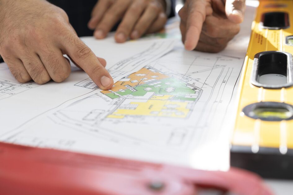 Personen zeigen auf einen Bauplan.