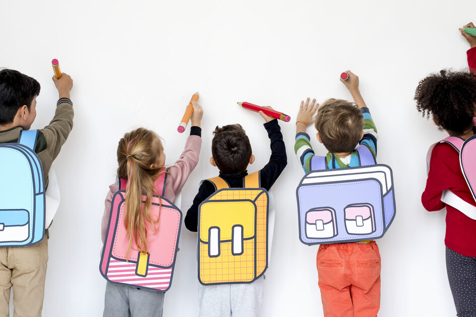 Kinder mit Schulranzen stehen an einer Wand.