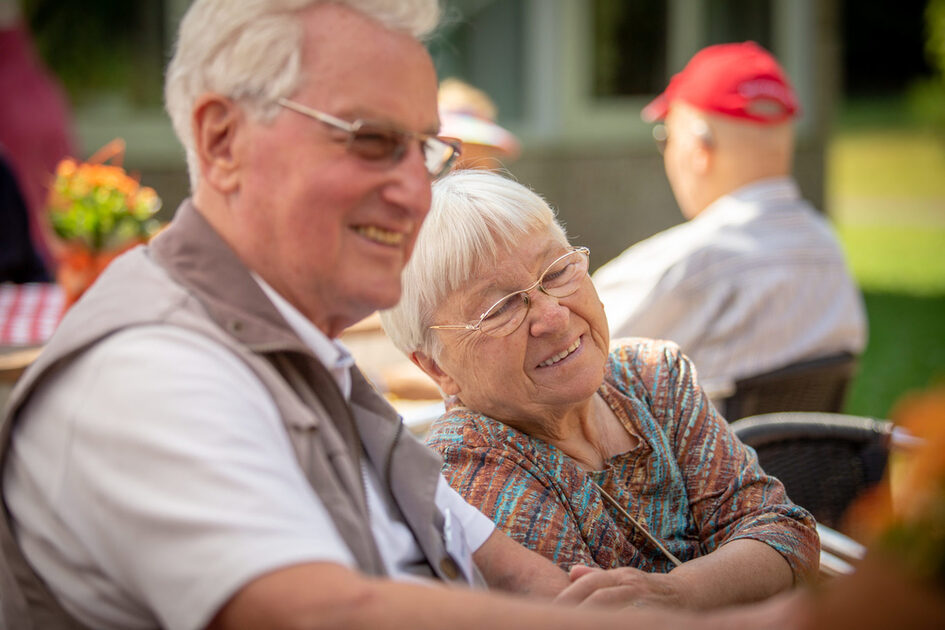 Elderly couple sitting in embrace.