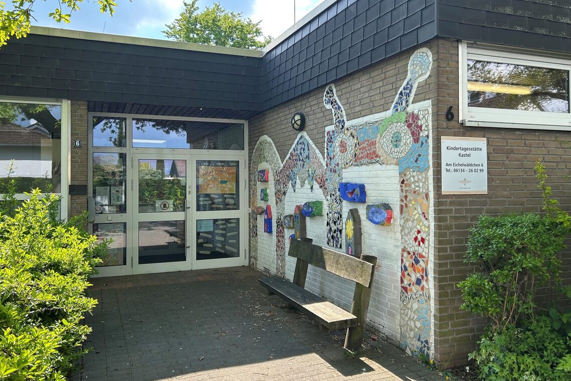 Der Eingang der Kindertagesstätte - an der rechten Wand ist ein Mosaik, davor steht eine Bank