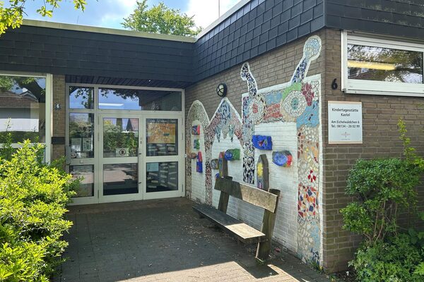 Η είσοδος του κέντρου ημερήσιας φροντίδας - υπάρχει ένα ψηφιδωτό στον δεξιό τοίχο με ένα παγκάκι μπροστά του