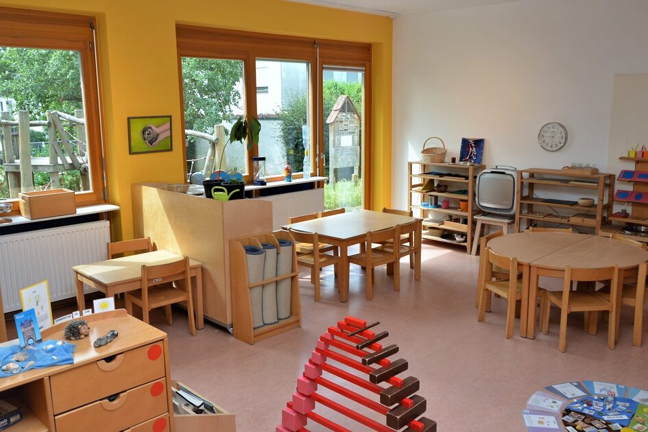 Ein Gruppenraum der Kindertagesstätte mit kleinen Tischen und Stühlen.