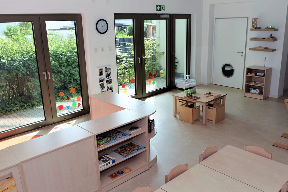 Eine Krippengruppe der Kindertagesstätte mit einer großen Fensterfront und en Blick in den Garten