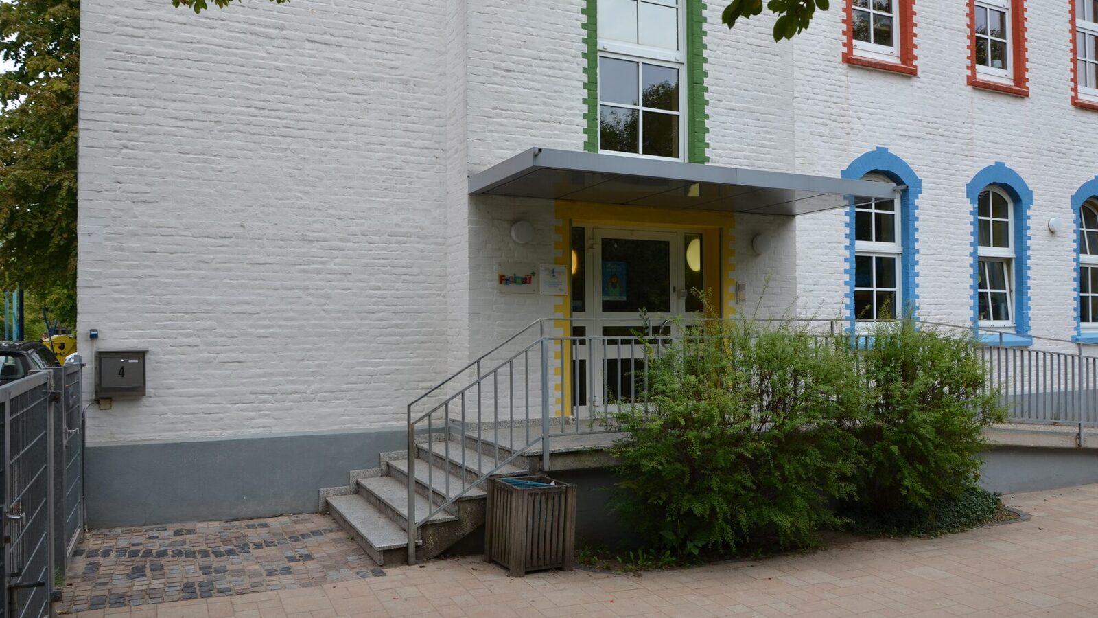 Der Eingangsbereich der Kindertagesstätte mit einer Treppe. Vor der Treppe stehen Pflanzen