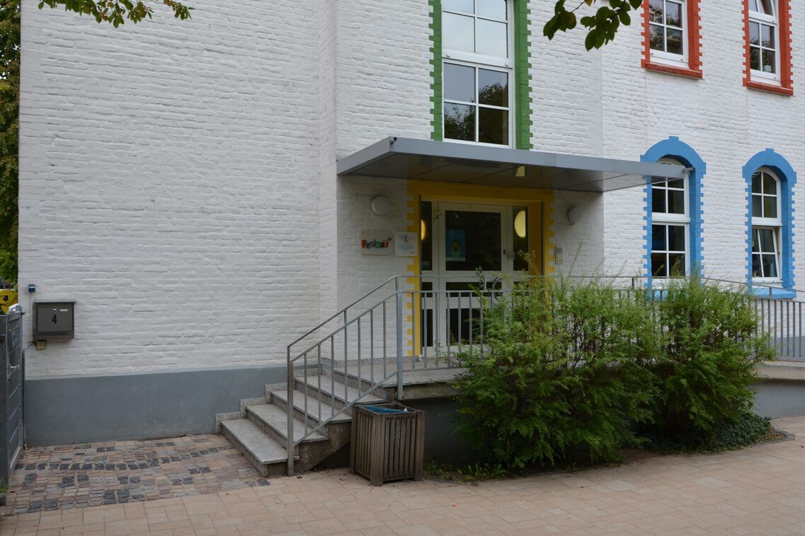 Der Eingangsbereich der Kindertagesstätte mit einer Treppe. Vor der Treppe stehen Pflanzen