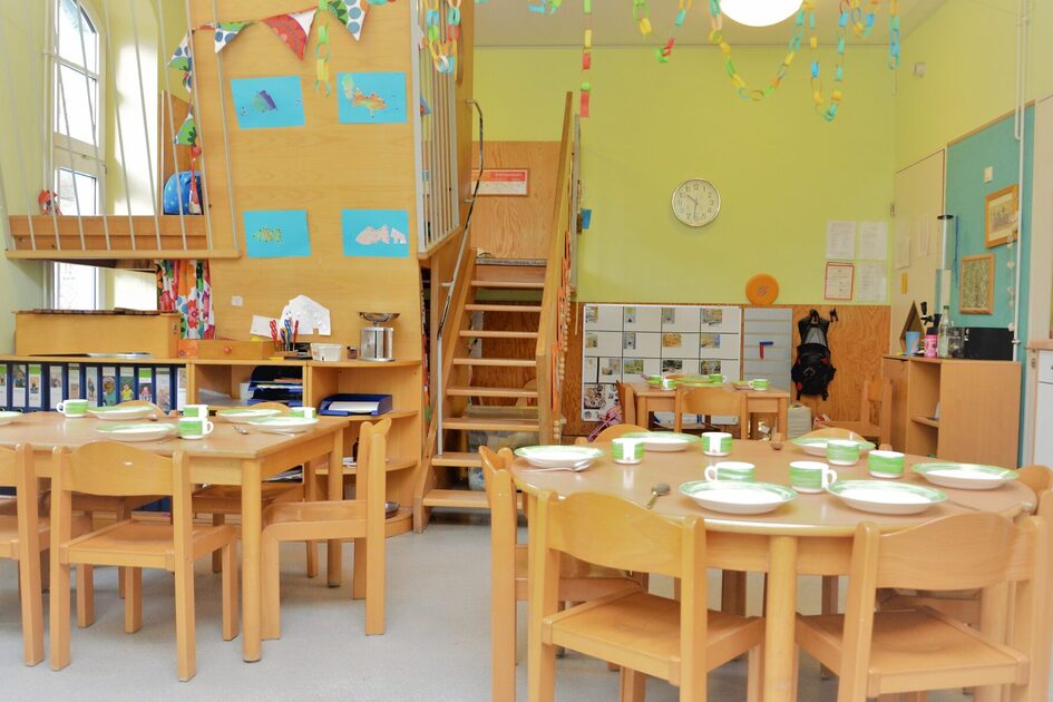 Ein Gruppenraum mit einer zweiten Ebene die über eine Treppe zu erreichen ist. Auf den beiden Tischen steht Geschirr