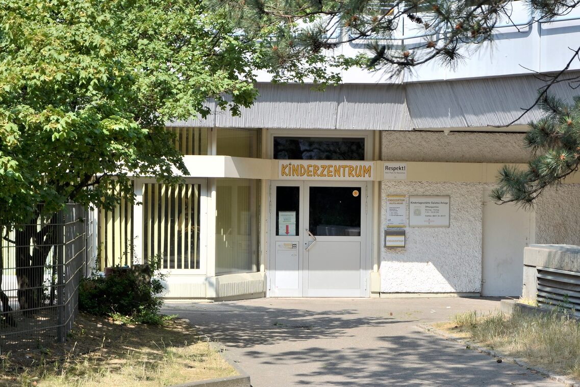 Entrance to the daycare center. On the outside area on the left is a tree whose branches reach over the path