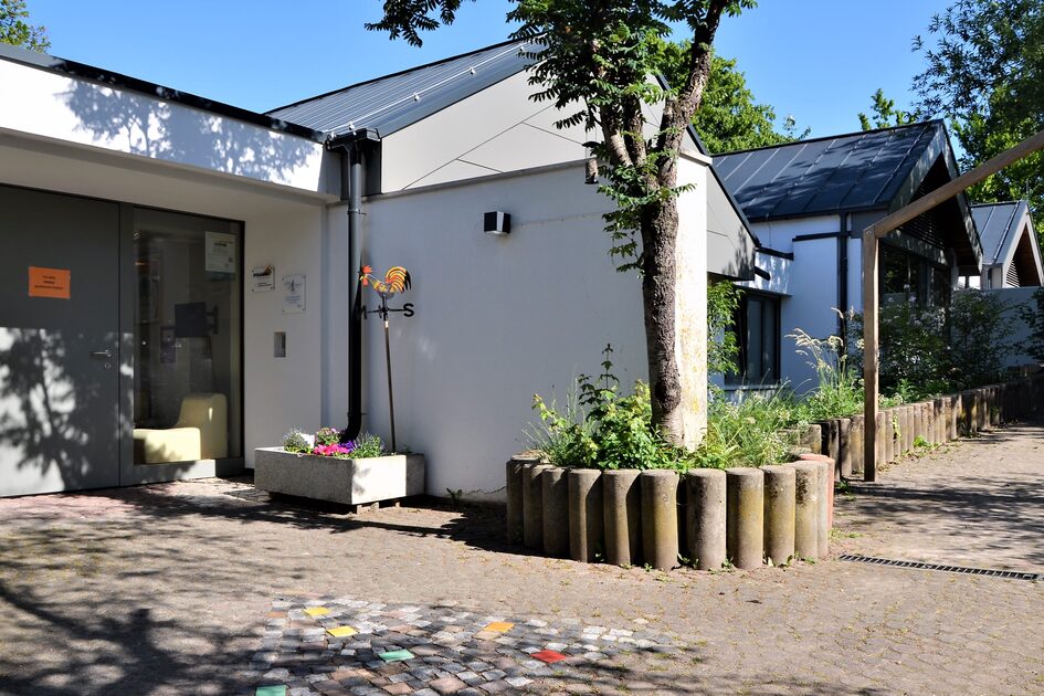 Das Außengelände der Kindertagesstätte mit altem Baumbestand. Im Hintergrund ist eine Hängebrücke