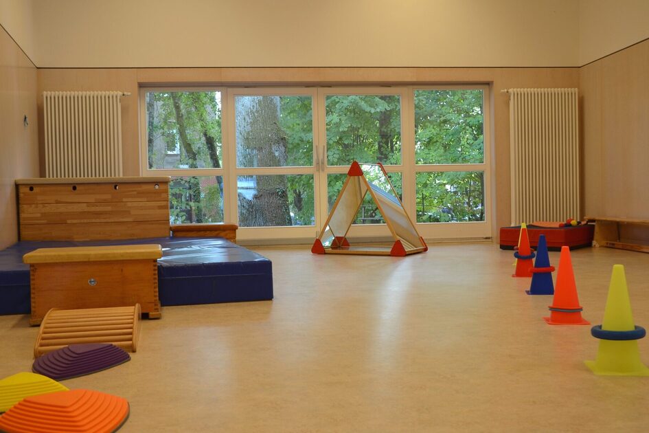 Der Bewegungsraum mit großen Matten, einem großen Springbock und Pylonen. Am Fenster steht ein Spiegelzelt.