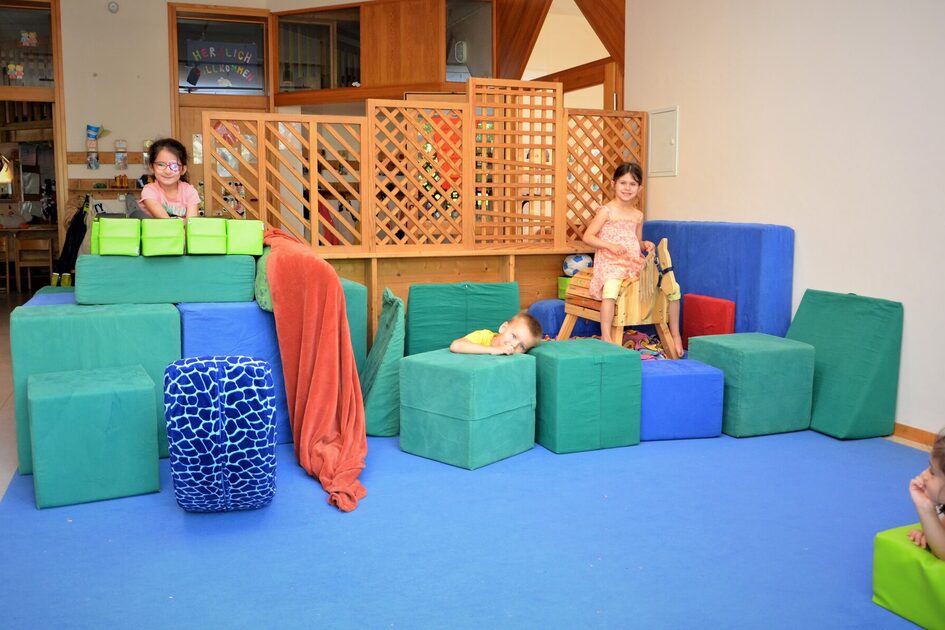 Im ersten Stock gibt es einen Spielflur. Auf einem blaueen Teppich stehen viele blaue und grüne Würfel Stoffwürfel zum bauen