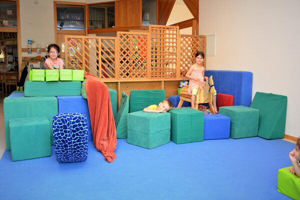 Im ersten Stock gibt es einen Spielflur. Auf einem blaueen Teppich stehen viele blaue und grüne Würfel Stoffwürfel zum bauen