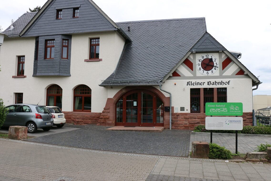 Das Gebäude der Kindertagesstätte ist in einem alten Bahnhof untergebracht. Rechts am Haus hängt noch die alte Bahnhofsuhr