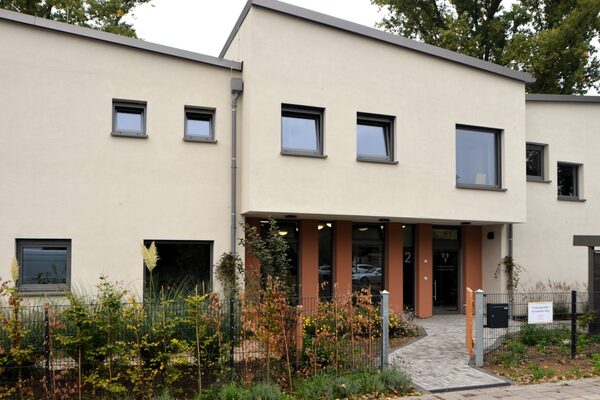 Das Gebäude mit dem Eingang der Kindergartenstätte. Durch das Tor gelangt man in einen kleinen Vorgarten. Ein Weg führt zur Eingangstür.