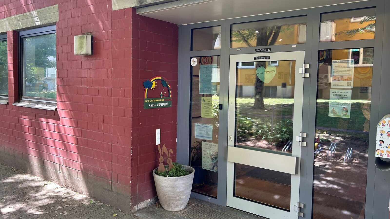 The entrance area of the daycare center. In the left-hand corner is a planter with the daycare center logo above it with the lettering
