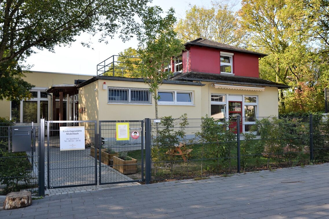 Der Eingangsbereich der Kindertagesstätte mit dem Tor und einem Schild mit dem Namen