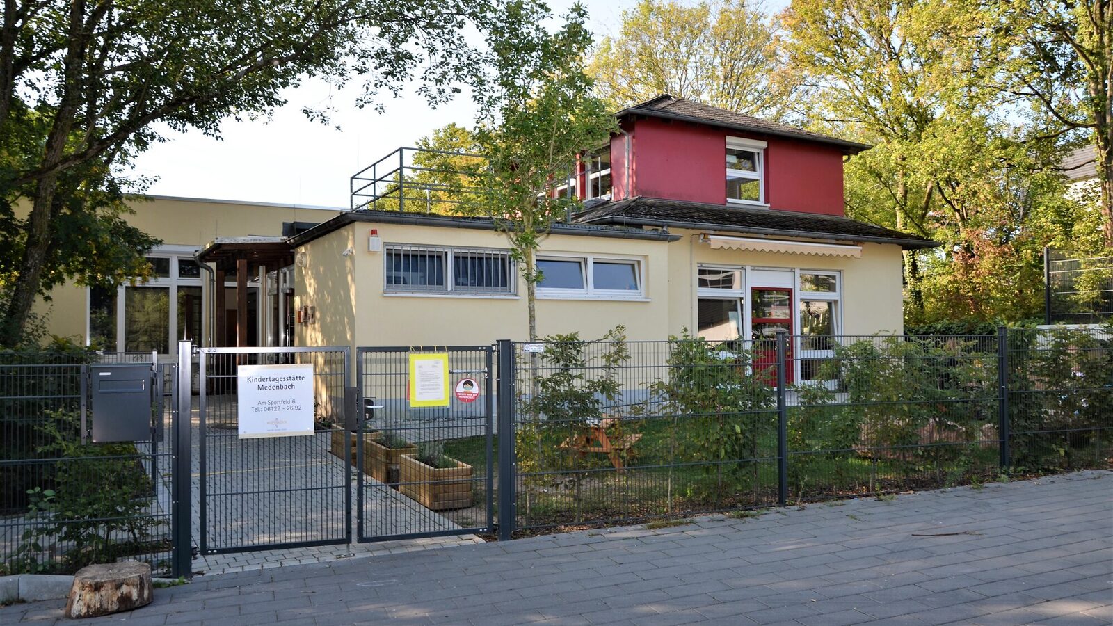 Der Eingangsbereich der Kindertagesstätte mit dem Tor und einem Schild mit dem Namen
