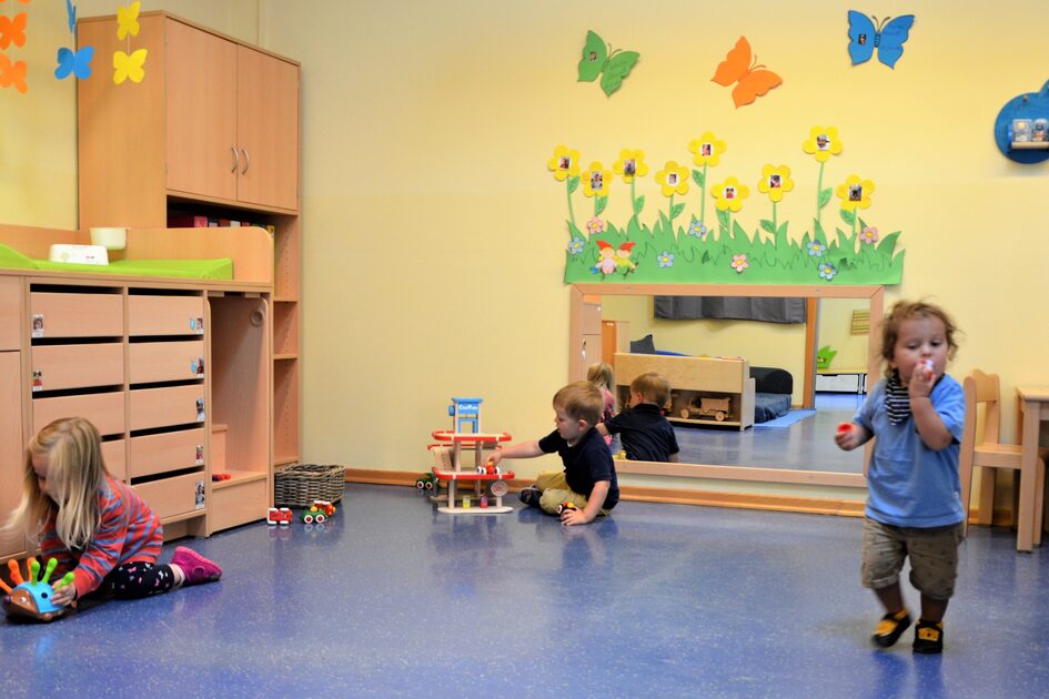 Dies ist der Gruppenraum der Krippe. Links steht ein großer Wickeltisch mit Schubladen, an der Wand hängt ein großer Spiegel