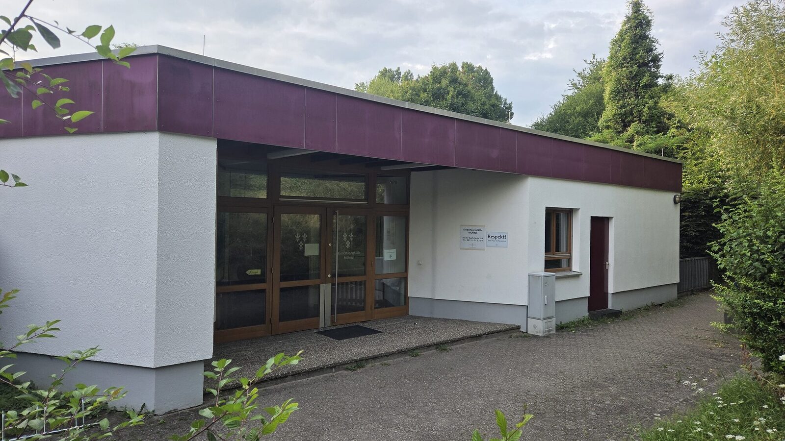 The entrance area of the daycare center. In the background are tall trees