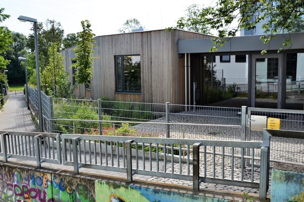 The entrance area of the daycare center is easily accessible via stairs and a ramp. The building is surrounded by trees and plants