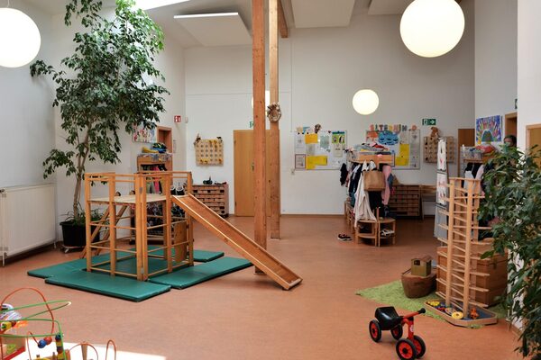Der Flur der Kindertagesstätte. In der Mitte steht ein Klettergerüst mit einer Rutsche. An der rechten Seite ist eine große Murmelbahn