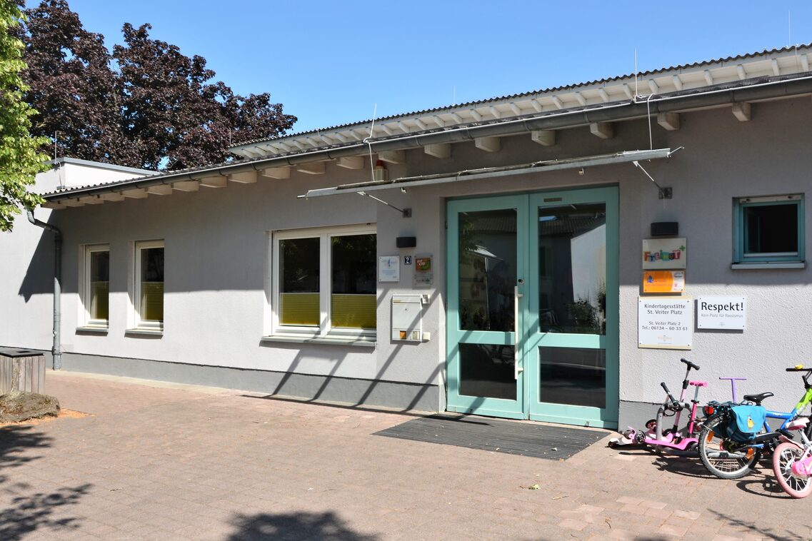 Le bâtiment de la crèche avec une porte d'entrée verte. Sur le côté droit se trouvent des vélos