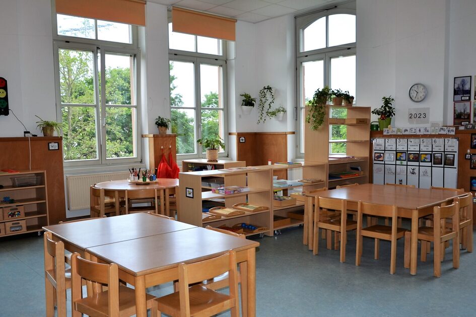 A group room in the elementary area with tables and chairs, with a shelf in the background as a room divider.