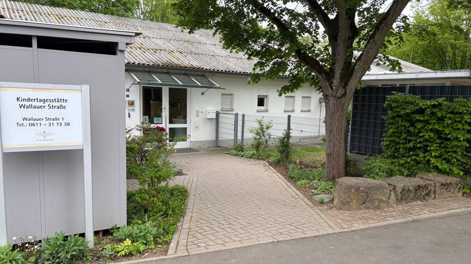 Der Eingangsbereich der Kindertagesstätte mit einem Schild und einem kleinen Vorgarten