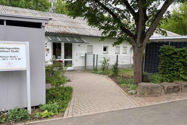 Der Eingangsbereich der Kindertagesstätte mit einem Schild und einem kleinen Vorgarten