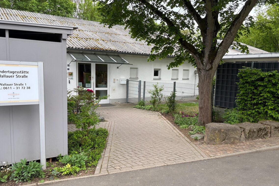 Der Eingangsbereich der Kindertagesstätte mit einem Schild und einem kleinen Vorgarten