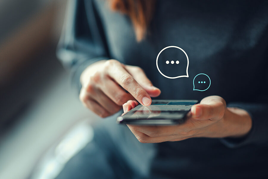 Frauenhand hält Smartphone in der Hand und Tippt etwas auf den Bildschirm.