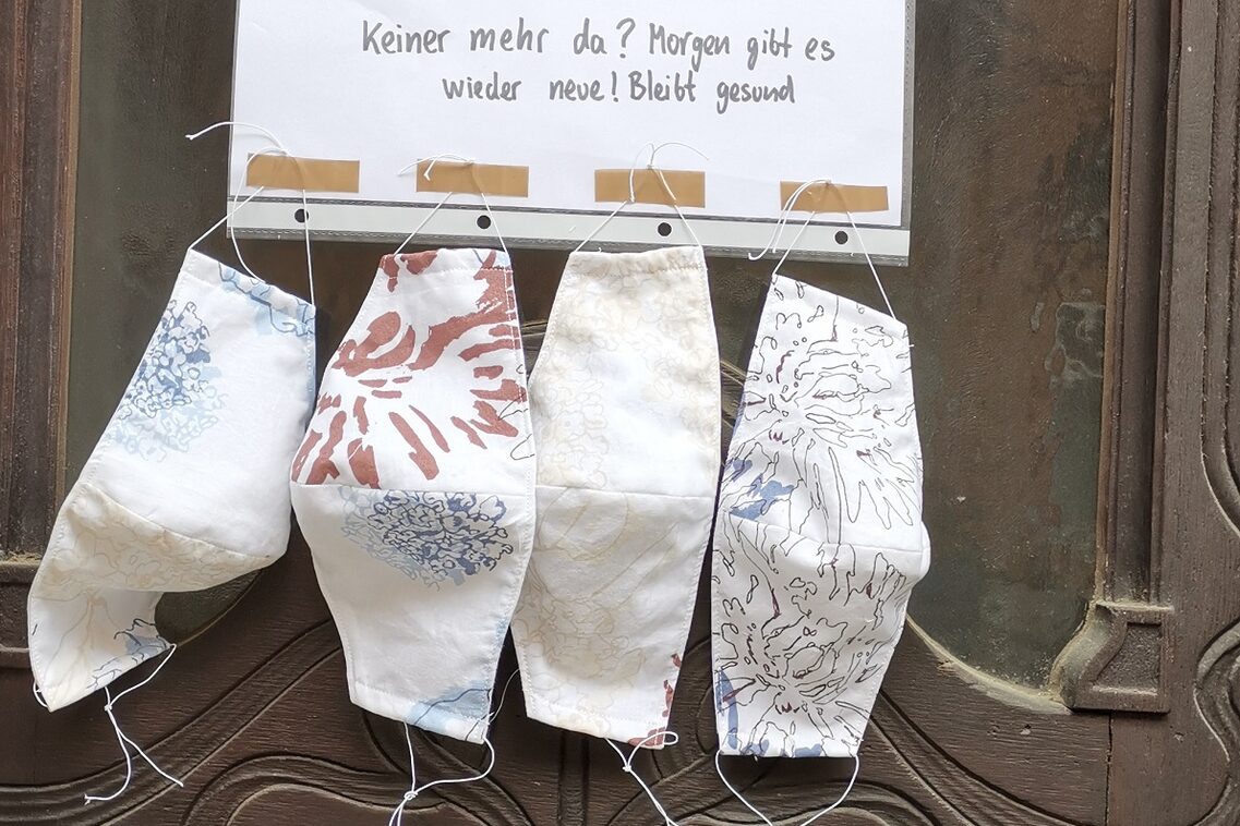 Masken an eine Haustür gehängt zum Mitnehmen angeboten