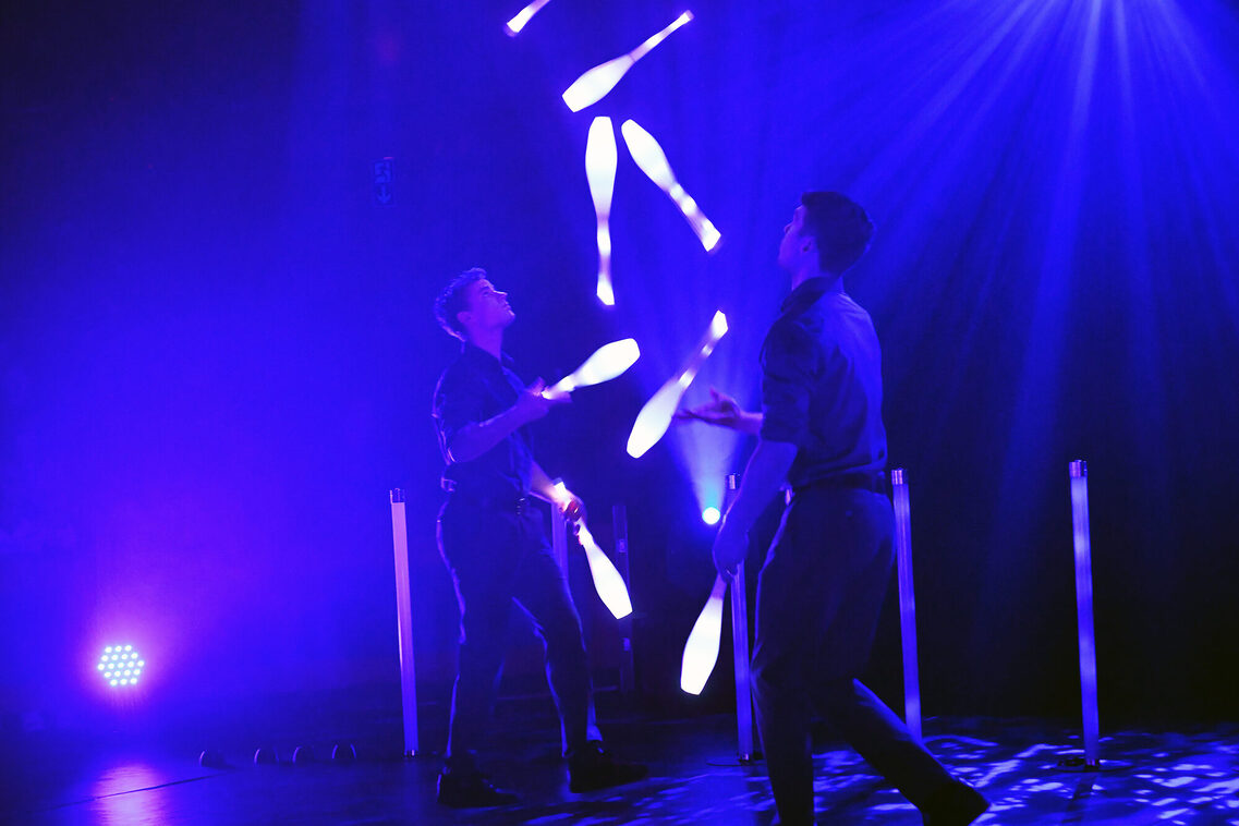 Jonglage Duo Fusion werfen sich LED-beleuchtete Keulen zu