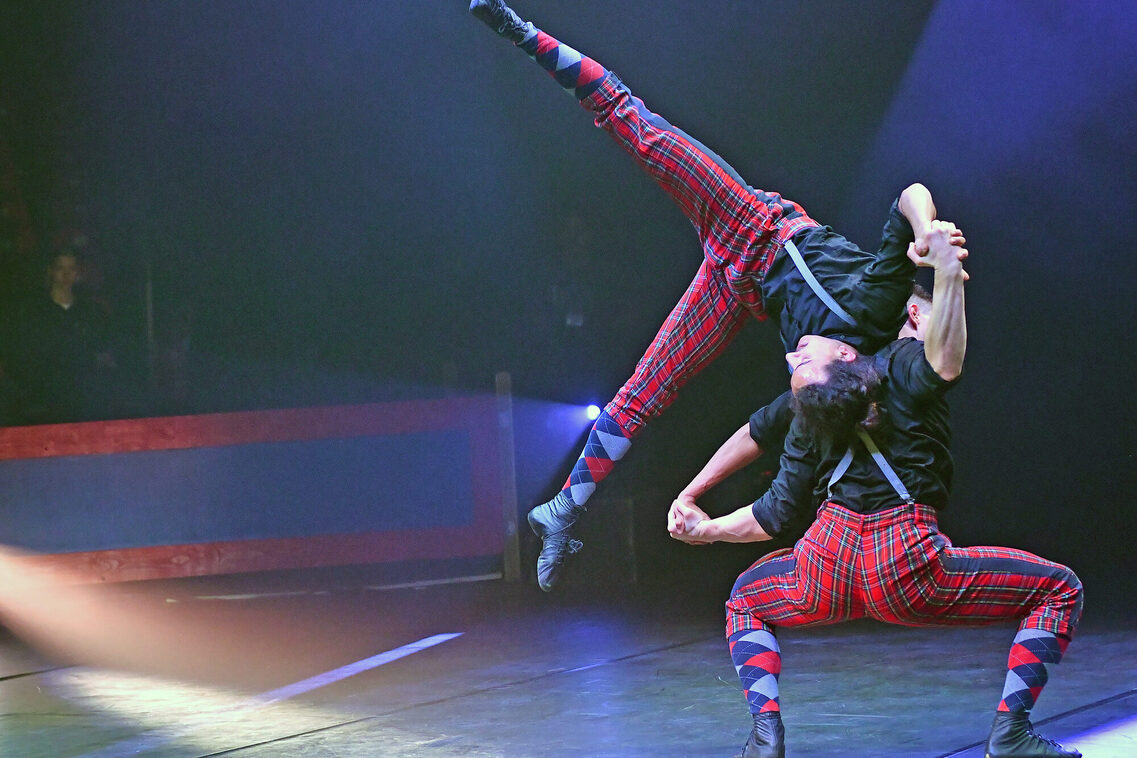 Duo Kraoul, beide in rot.-blau karierten Hosen und schwarzem Hemd bei der Partnerakrobatik